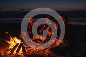 Young friends have picnic with bonfire on the beach