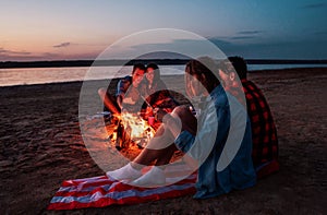 Young friends have picnic with bonfire on the beach