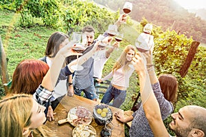 Young friends having fun outdoors drinking red wine at vineyard winery