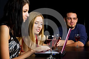 Young friends with laptop in a bar.