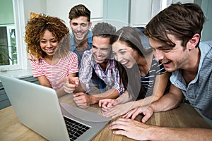 Young friends laughing while looking in laptop on table