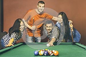 Young friends playing pool at billiard table saloon - Happy friendship