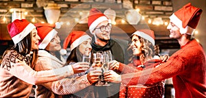 Young friends with santa hats celebrating Christmas with champagne wine toast at home reunion - Winter holidays concept