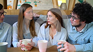 Young friends sit in a cafe, drink coffee and have fun communicating