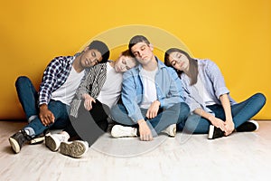 Young Friends Sitting Together and Resting Against a Yellow Wall