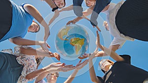 Young friends surround the globe of the world with their palms. The concept of preserving world peace.