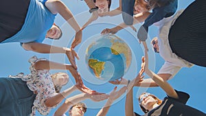 Young friends surround the globe of the world with their palms. The concept of preserving world peace.