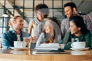 Young friends at table in cafe their smartphones lying in pile on table