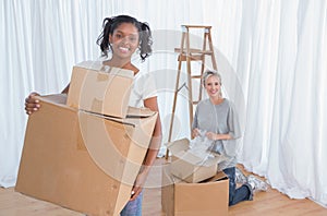 Young friends unpacking in their new home and smiling at camera