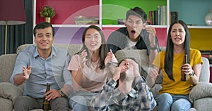 Young friends watching football game on TV together at home and disappointed about their favourite team losing match