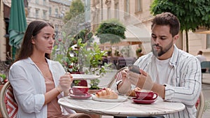 Young frustrated disappointed woman upset offended drinking coffee city outside cafe Caucasian separated man busy mobile