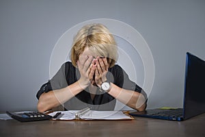 Young frustrated and stressed business woman crying sad at office desk working with laptop computer overwhelmed by paperwork workl