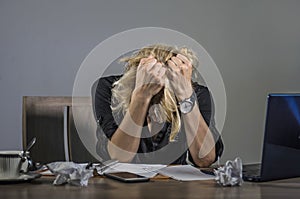 Young frustrated and stressed business woman crying sad at office desk working with laptop computer overwhelmed by paperwork workl