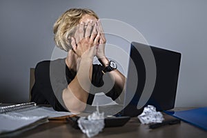 Young frustrated and stressed business woman crying sad at office desk working with laptop computer overwhelmed by paperwork workl