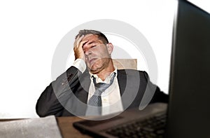 Young frustrated and stressed businessman in suit and tie working overwhelmed at office laptop computer desk desperate and worried