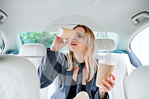 Young frustrated woman with empty paper glasses sitting in car.