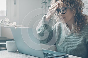 Young frustrated woman working at office desk in front of laptop suffering from chronic daily headaches, treatment online,