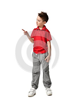 Young full body boy kid in red polo t-shirt standing pointing one finger at the corner isolated on white