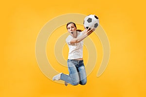 Young fun expressive European woman football fan jumping in air, cheer up support team, holding soccer ball isolated on