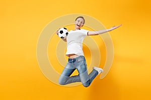 Young fun expressive European woman football fan jumping in air, cheer up support team, holding soccer ball isolated on