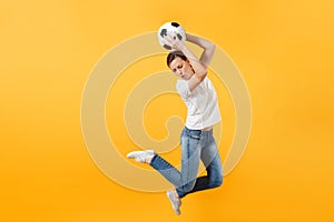 Young fun expressive European woman football fan jumping in air, cheer up support team, holding soccer ball isolated on