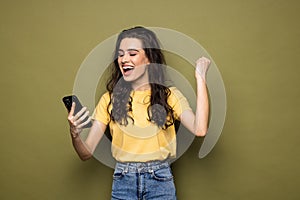 Young fun happy womanhold mobile cell phone with blank screen isolated on khaki background studio