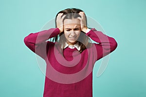 Young fun sad upset perplexed disturb brunette woman girl put hands on head posing isolated on blue wall background