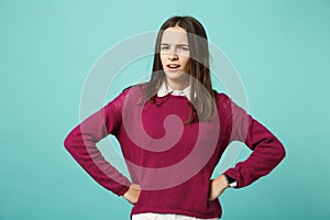 Young fun sad upset perplexed disturb brunette woman girl standing with arms akimbo on waist posing isolated on blue