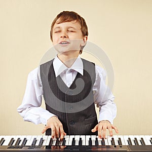 Young funny boy in a suit playing electronic synthesizer