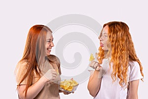 Young funny caucasian two women holding potato chips, Fast food banner concept. Redhaired girl sticking tongue out happy