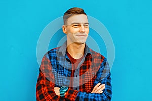 Young funny cheerful man with a stylish hairstyle with a cute smile in a fashionable t-shirt in a vintage checkered colorful shirt