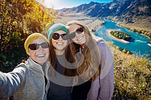 Young funny europian girls in sunglasses against mountain landscape make selfie, family travel and adventure, vacation concept photo