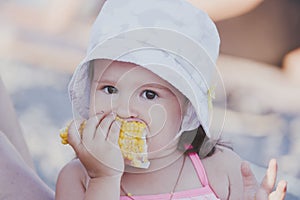 Young funny girl eating a boiled corn