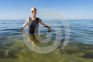 A young funny girl in a neoprene suit swims in the cold Baltic Sea photo
