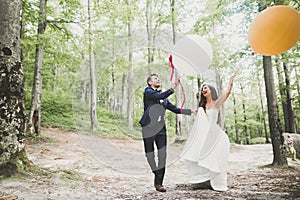 Young funny happy wedding couple outdoors with ballons