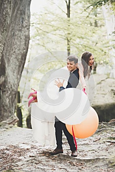 Young funny happy wedding couple outdoors with ballons