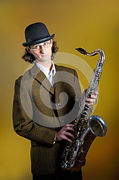 young funny man in bowler hat holding saxophone photo