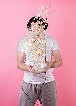 Young funny man throwing popcorn into the air isolated on pink