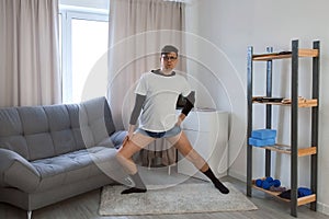 Young funny nerd man in glasses doing fitness lunge exercise for legs at home.