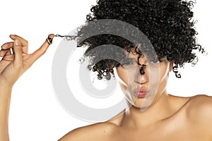 Young funny woman with black curly wig on white