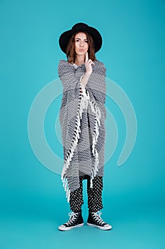 Young funny woman in hat covered in blanket standing