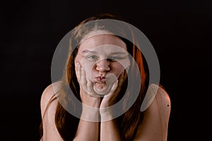 Young funny woman puff out and pop cheeks. Female portrait isolated on black. Cheerful girl pout and make faces.