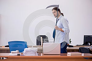 Young male furious employee holding axe in the office photo