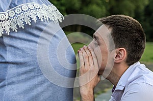 Young future dad talking to an unborn baby in the belly of a pregnant mom