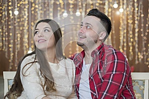 Young future parents on the background of bright lights of garlands.