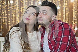 Young future parents on the background of bright lights of garlands.