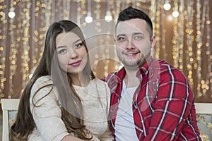 Young future parents on the background of bright lights of garlands.