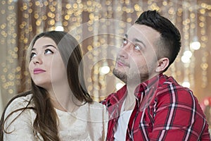 Young future parents on the background of bright lights of garlands.