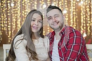 Young future parents on the background of bright lights of garlands.