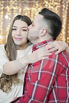 Young future parents on the background of bright lights of garlands.